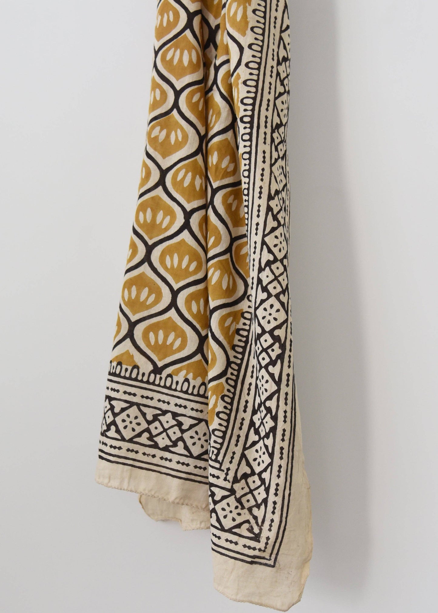 A yellow sarong with black and cream patterns, displayed vertically against a white background.